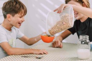 bambino sorrideva mentre gli viene riempita la tazza di cereali