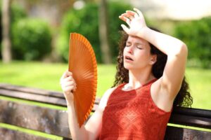 una signora seduta sulla panchine che sente caldo