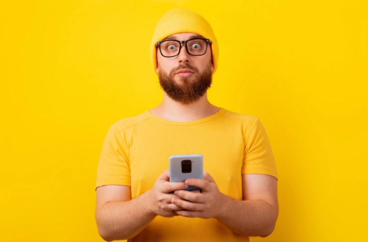 uomo con il cellulare in mano e l'espressione scioccata