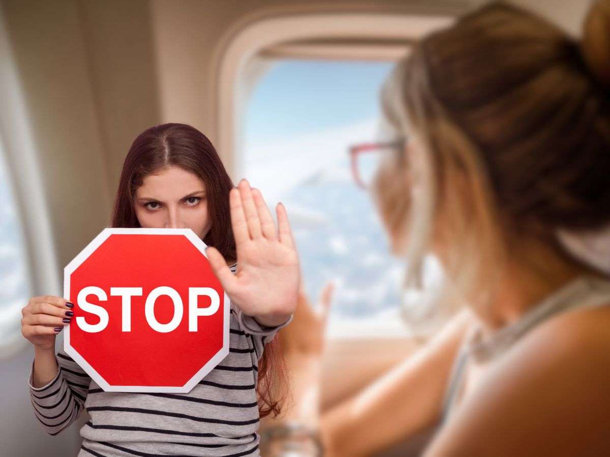 donna in aereo e un'altra con cartello stop