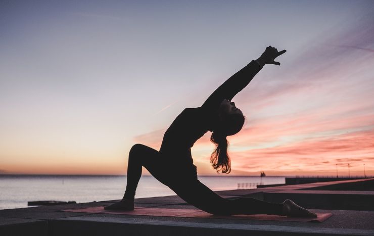ragazza yoga stretching tramonto