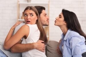 donna abbracciata al fidanzato che cerca di baciare un'altra donna