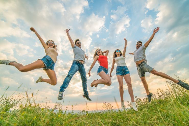 5 ragazzi che si trovano in un parco prima del tramonto, foto di loro che saltano