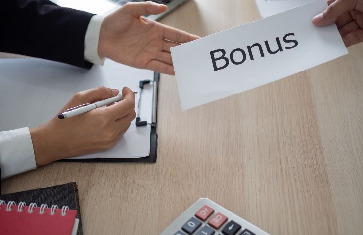 una persona che passa una busta con la scritta bonus