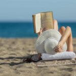 donna che legge libro in spiaggia