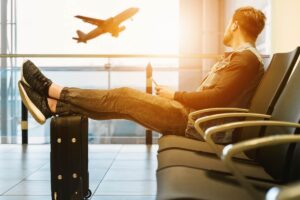 uomo all'aeroporto con la valigia seduto che aspetta il suo volo