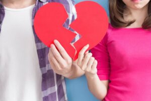 Coppia con cuore di cartone in mano spezzato