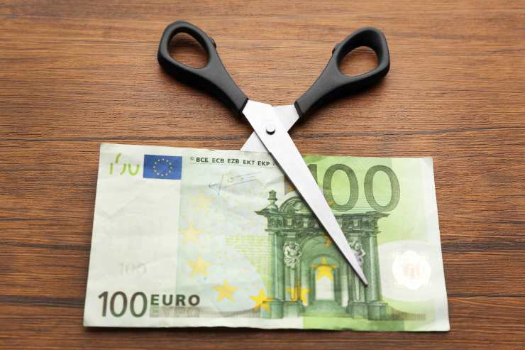 una forbice con in mezzo una banconota da 100 euro