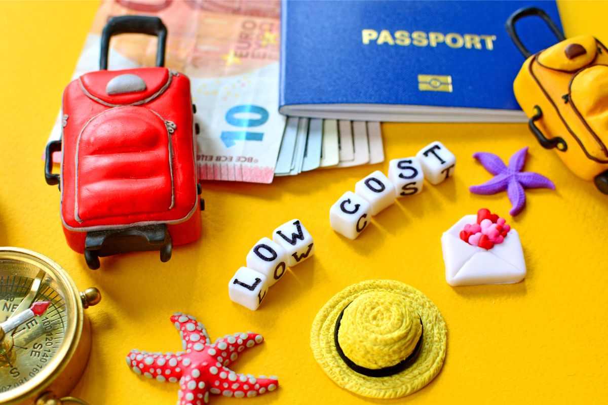 una valigia, dei soldi, un passaporto e la scritta viaggi low cost
